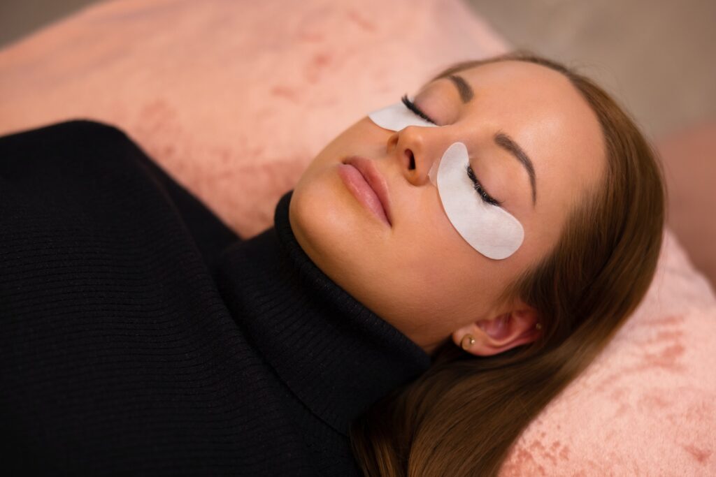Woman With Cotton Pads Lying During Eyelash Extension Procedure